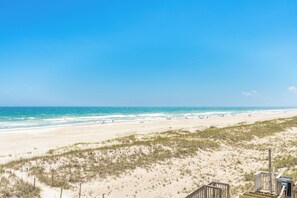 A beach with a wooden boardwalk leading to the water, sandy dunes, and a clear blue sky. - Ocean Potion - Oceanfront Queen's Grant Condo with Amazing Views! (Topsail Beach)