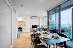 Apartamento moderno com área de jantar, cozinha e grandes janelas com vista para a cidade.