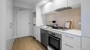 A modern kitchen with white cabinetry, a built-in oven, and a gas stove. - City Living At Best Location In Melbourne (Melbourne)