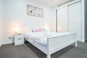 Een moderne slaapkamer met een wit bed, nachtkastjes en een wanddecoratie van herten.