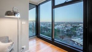 A modern room with large windows offering a city view, a floor lamp, and a grey sofa. - Sweet Apartment At Centro Melbourne (Melbourne)