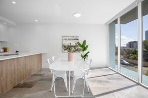 Eine moderne Küche mit weißer Arbeitsplatte, einem Holzschrank und einem großen Fenster mit Blick auf die Stadt.