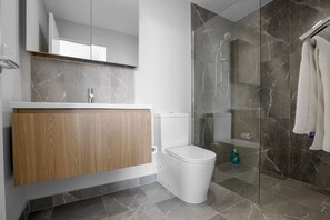 Ein modernes Badezimmer mit Waschtisch aus Holz, Toilette in Weiß und einer Duschkabine.