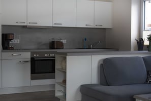 A modern kitchen with white cabinets, a built-in oven, a coffee maker, and a toaster.