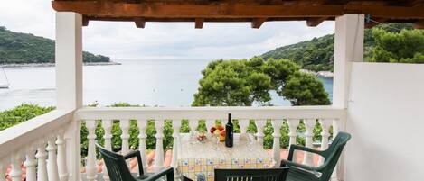 A balcony with a table set for two, overlooking a body of water and greenery.