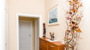 A hallway with a wooden dresser, a door, and a wall-mounted decorative piece. - Rooms Lydia - Adults Only (Dubrovnik)