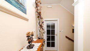 A narrow hallway with a wooden table, a doily, and a vase with dried flowers. A door with a frosted glass panel is visible. - Rooms Lydia - Adults Only (Dubrovnik)