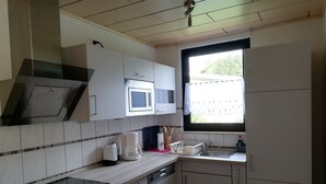 Een moderne keuken met witte kastjes, een magnetron, een koffiezetapparaat en een spoelbak.