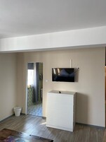 Habitación con una televisión de pantalla plana montada en la pared, un aparador blanco y suelo de madera.