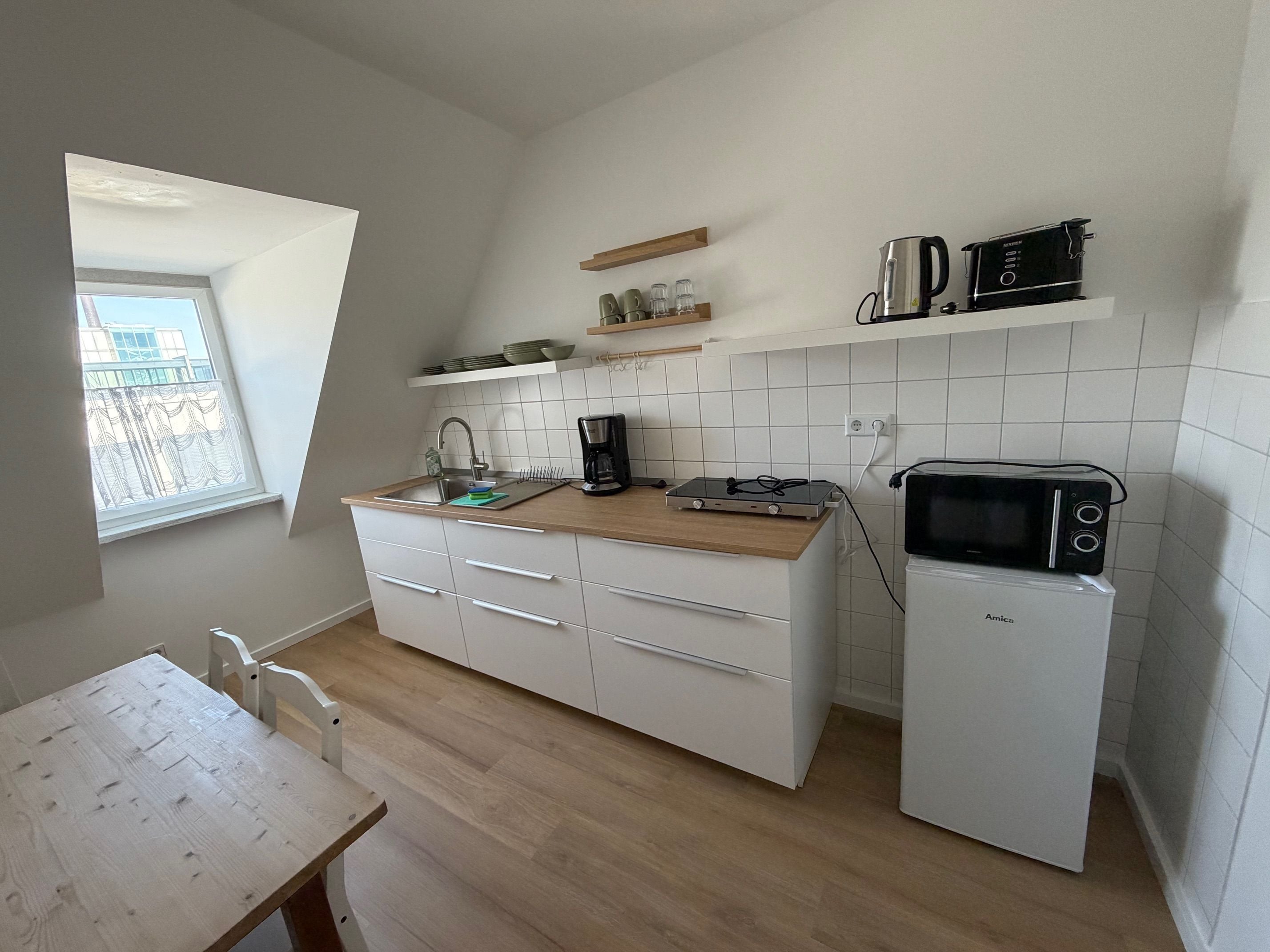 A compact kitchen with a built-in microwave, coffee maker, and a small sink.