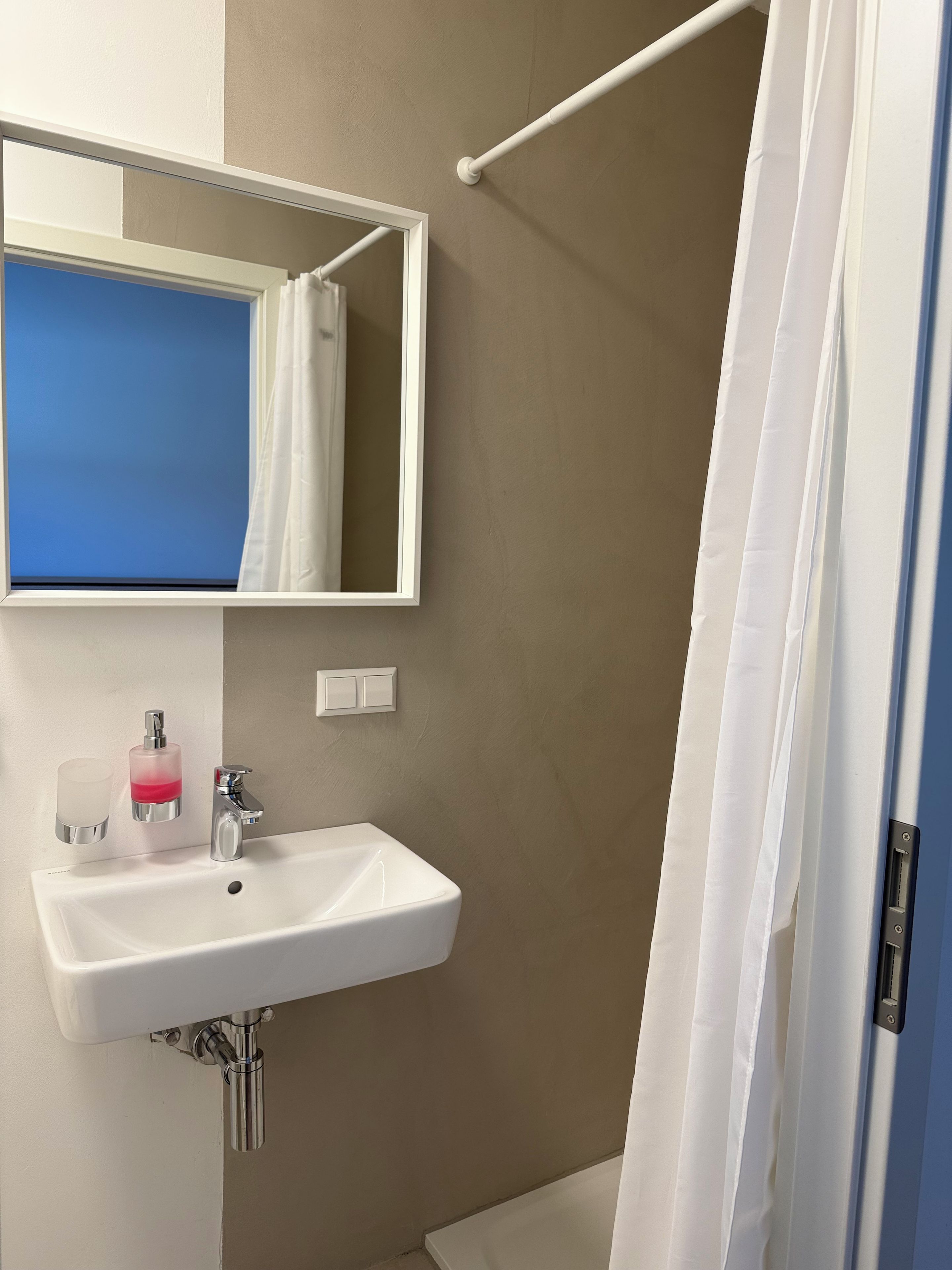 A bathroom with a white sink, a mirror, a towel rack, and a shower curtain.