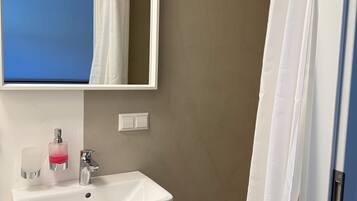 A bathroom with a white sink, a mirror, a towel rack, and a shower curtain.