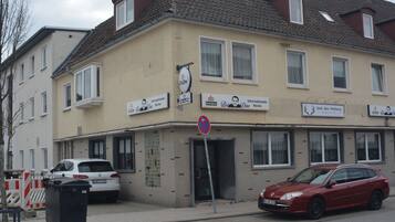 Un bâtiment avec de nombreuses fenêtres, un panneau indiquant qu’il est interdit de se garer, et une voiture rouge stationnée devant.