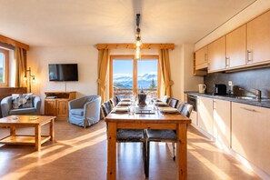 Un salon chaleureux avec un coin repas, des meubles en bois, un téléviseur à écran plat et une cuisine dotée de meubles en bois.