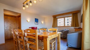 A wooden dining table with chairs, a red bowl, and a blue sofa in a room with wooden floors and a window. - Pracondu 1 101 - OUTDOOR & FUN  apartment 8 pers (Haute-Nendaz)