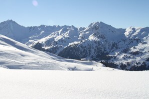 Een berglandschap bedekt met sneeuw, met skipistes en een heldere lucht.
