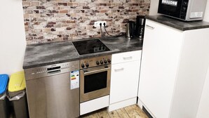 A compact kitchen with a brick backsplash, a Siemens dishwasher, a stove, and a microwave. - City Apartment S & W (Hamburg)
