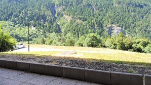 A view of a forested mountain area with a road and a white car parked on the side.