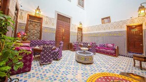 A traditional Moroccan interior with patterned tile flooring, ornate doors, and colorful cushions. - Riad Baba (Fes)