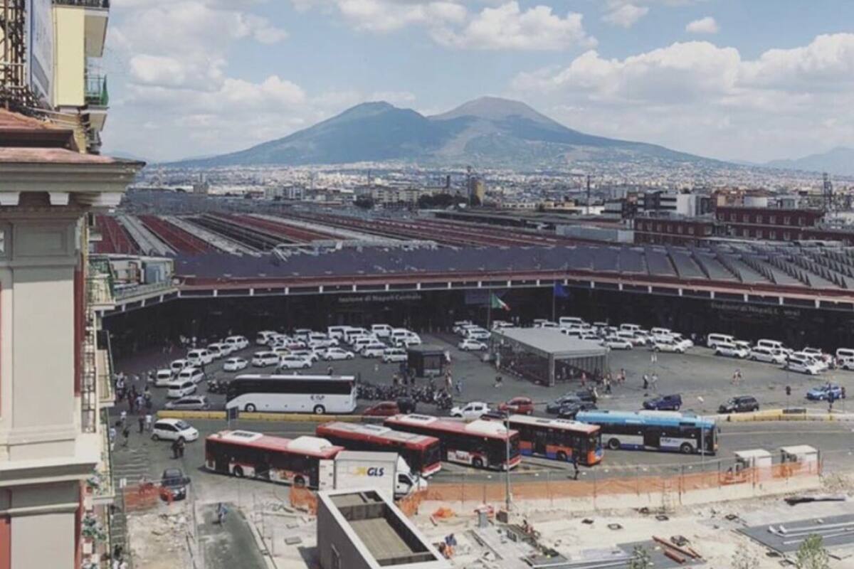 A view of a train station with multiple tracks and a large building in the foreground.