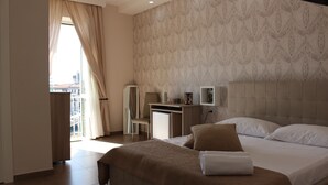 A hotel room with a bed, a desk, and a view of the city. - Philip Royal (Naples)