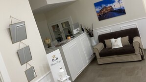 A modern living area with a sofa, a kitchen area, and a dining table. - Philip Royal (Naples)