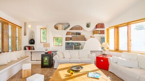 A modern living room with a white sofa, a wooden coffee table, and a bookshelf filled with books. - Villa Ixia (Rhodes)