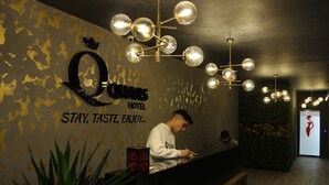 A hotel reception area with a modern chandelier, a reception desk, and a wall with the hotel's name and slogan. - Quars Suite (Istanbul)