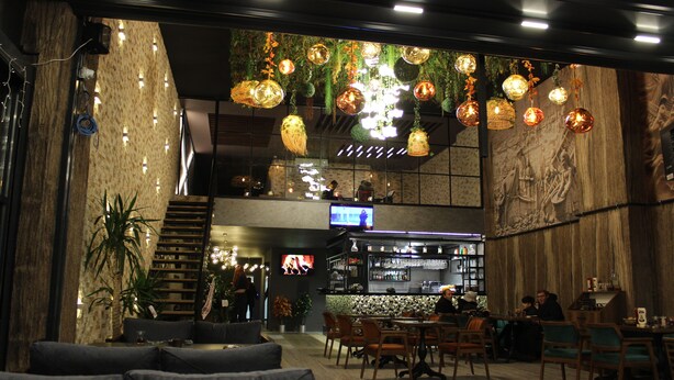 A restaurant with a bar area, seating, and a TV screen. - Quars Suite (Istanbul)