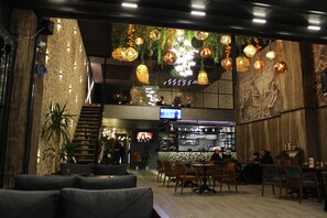 Un restaurant doté d’un bar, de tables et d’un écran de télévision.