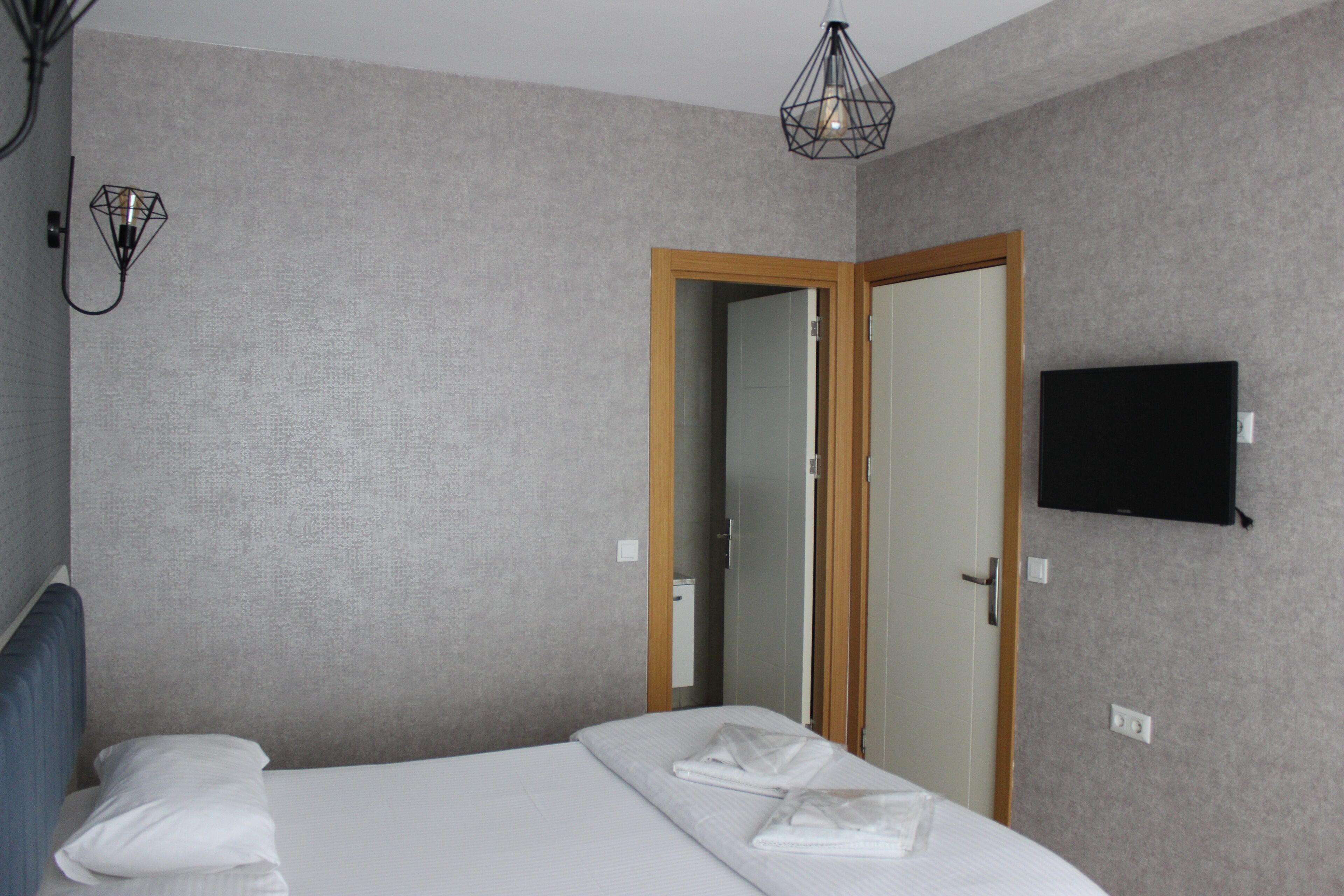 A hotel room with a bed, a television mounted on the wall, and a door leading to another room.