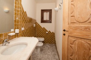 A bathroom with a sink, toilet, and a wooden door. - Villa Pevero Hills 4 (Arzachena)