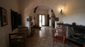 A room with a tiled floor, a fireplace, and a wooden chair. - Villa Scarabeo (Maracalagonis)