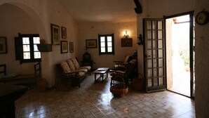 A cozy living room with a sofa, chairs, a table, and a door leading outside. - Villa Scarabeo (Maracalagonis)