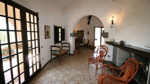 A room with a tiled floor, wooden chairs, a fireplace, and a view through a window. - Villa Scarabeo (Maracalagonis)