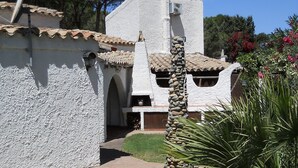Un edificio rústico con fachada de piedra, techo de tejas y un pilar de piedra en primer plano.