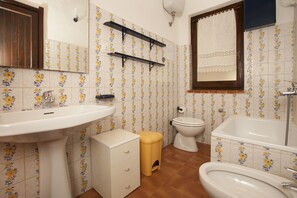 A bathroom with a sink, toilet, bathtub, and shelves.