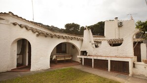 Un patio con un banco, paredes blancas y techo de tejas.