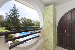 Vista desde un balcón con una piscina de piedra, una puerta de madera y un árbol grande.