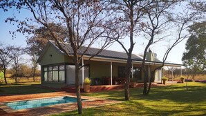 Une maison avec une piscine, entourée d’une pelouse bien entretenue et d’arbres.