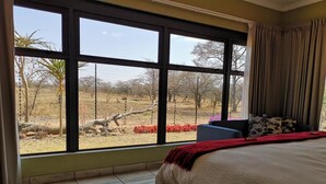 Une chambre dotée d’une grande fenêtre, d’un lit et offrant une vue sur un paysage extérieur.