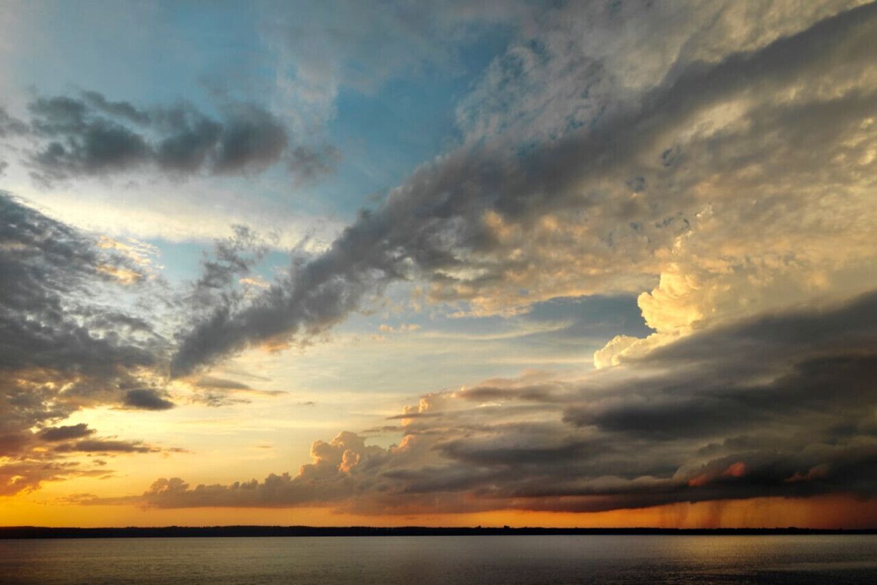 Un atardecer sobre un cuerpo de agua tranquilo con un horizonte despejado.