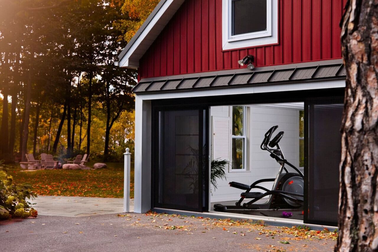 A red building with a garage door open, revealing a stationary exercise bike inside.
