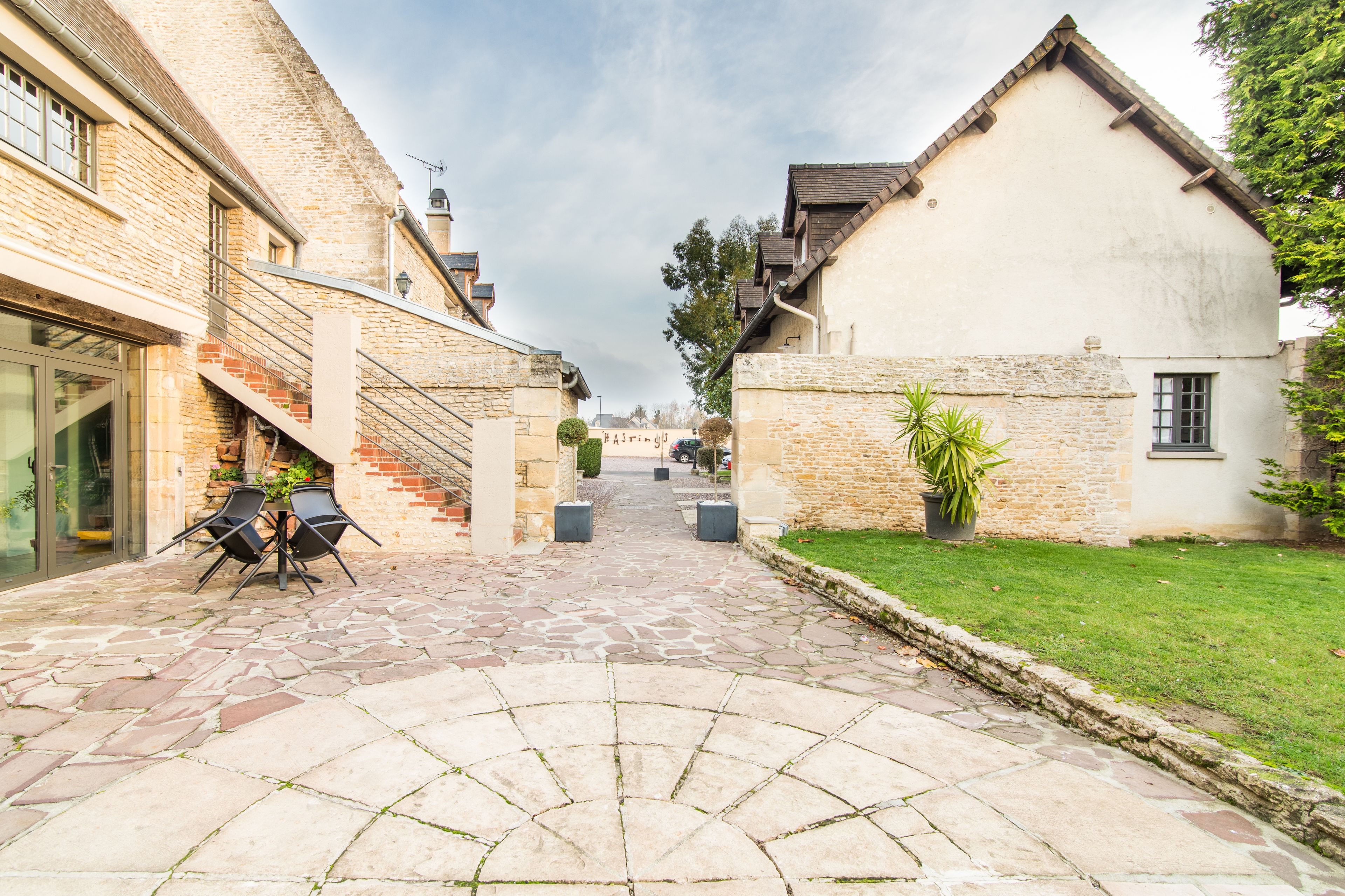 A courtyard with stone flooring, two outdoor tables, and chairs.