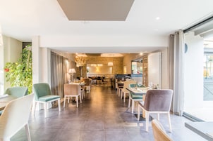 Un restaurante moderno con una barra larga, varias zonas de estar y una pared de ladrillo al fondo.