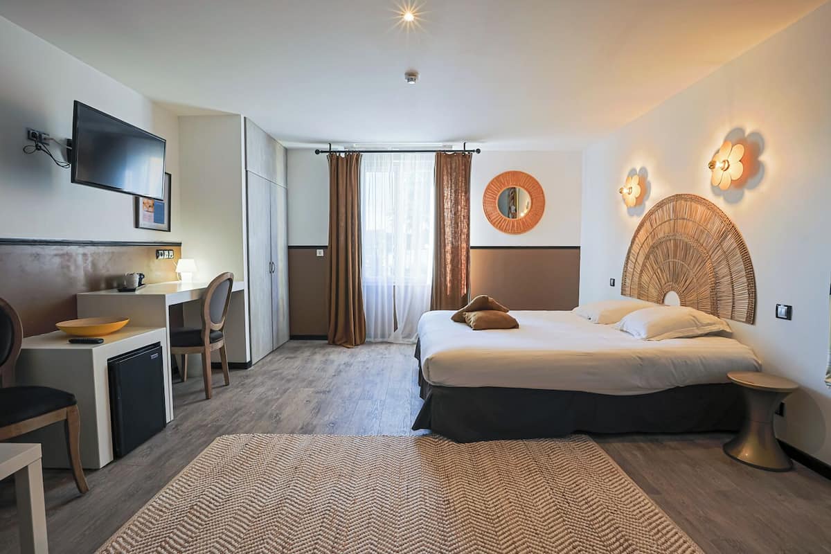 Een hotelkamer met een bed, bureau, stoel, televisie en een badkamer.