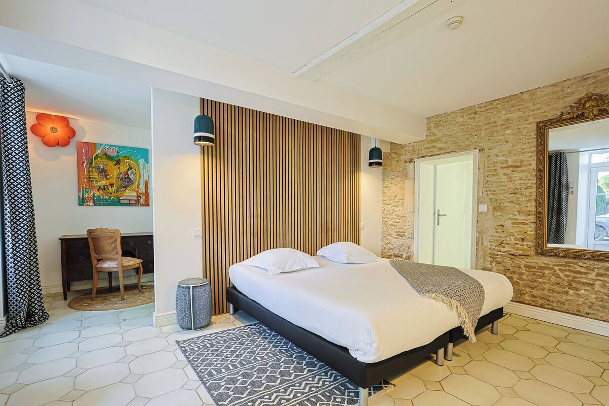 Een moderne slaapkamer met een bed, bureau en stoel.
