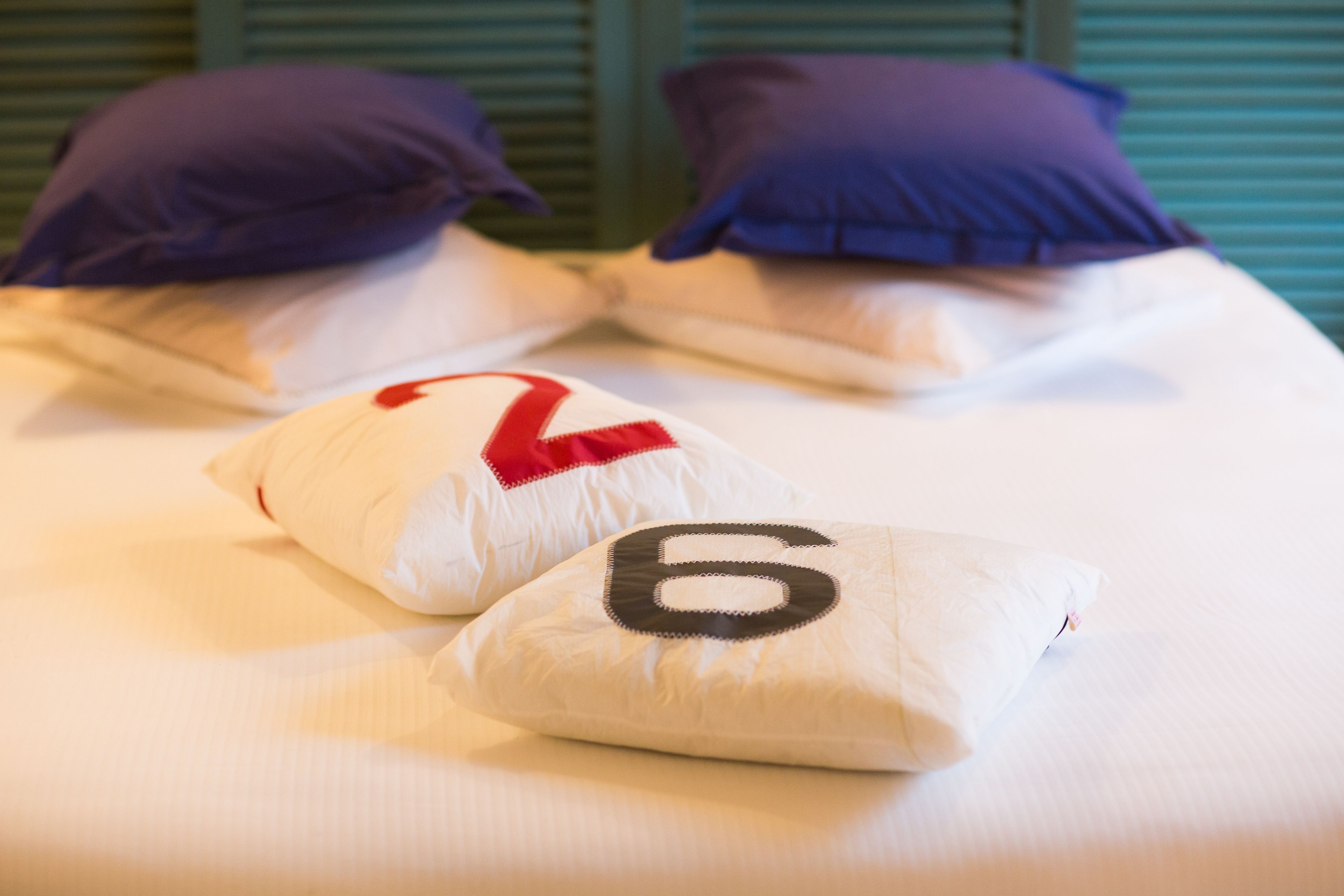 A bed with two pillows, one with a red number 2 and the other with a black number 6.