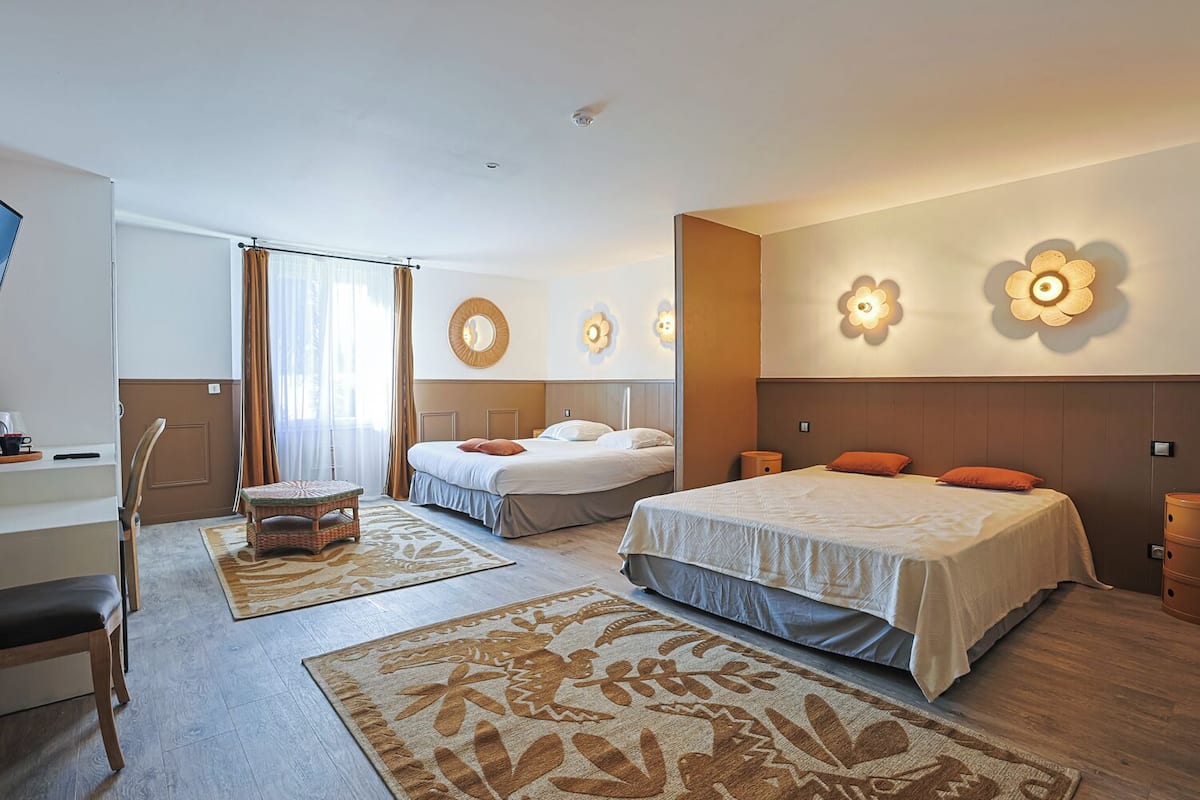 Een hotelkamer met twee bedden, een bureau, een stoel en een tafeltje.