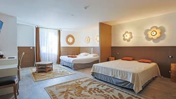 A hotel room with two beds, a desk, a chair, and a small table.